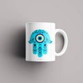 Hamsa Blessing Mug – "Hamsa hand ceramic mug featuring an evil eye symbol, representing luck, spiritual protection, and positivity."